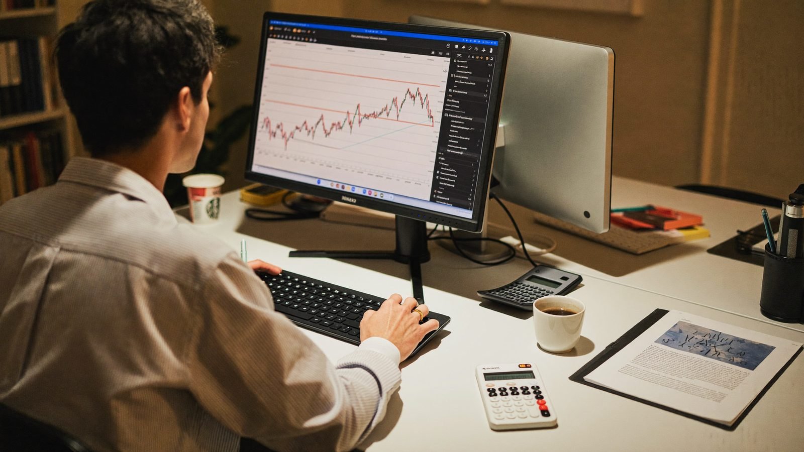 Treuhand-Arbeitsplatz mit zwei Monitoren, Taschenrechner und Kaffee