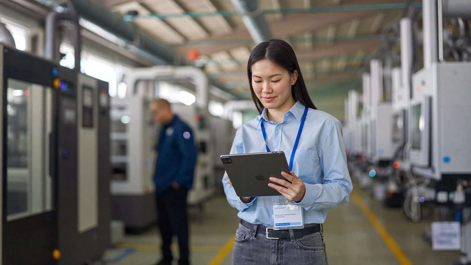 Betriebsleiter und Mitarbeiterin mit Tablet in einer Produktionshalle